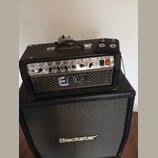 Černý kytarový zesilovač s nápisem ENGL na přední mřížce, umístěný na černém kytarovém reproduktoru značky Blackstar. Zesilovač má kovový ovládací pa…