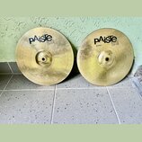 Dvě mosazné činely typu hi-hat v zlatavé barvě s koncentrickým žilováním. Oba mají černý nápis pAiste 101 BRASS a pod ním označení 12" HI-HAT. Povrch…