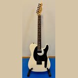 Bílá elektrická kytara s černým pickguardem a hnědým hmatníkem. Na hlavě je viditelné logo Fender a na pickguardu nápis Fender Mono-caster. Nástroj j…