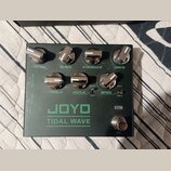 Tmavě zelený kytarový efekt s nápisem JOYO TIDAL WAVE. Na horní straně jsou čtyři chromované ovratovky s popisky LEVEL, BLEND, PRESENCE a DRIVE. Ve s…