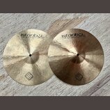 Dvě mosazné činely s viditelným rýhováním povrchu. Oba mají nápisy istanbul Agop Handmade cymbals from Turkey a v dolní části logo TRADITIONAL. Povrc…