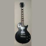 Černá elektrická kytara typu Les Paul s bílým lemováním korpusu. Na hlavě je viditelné logo Ligmand. Nástroj má dva humbuckery, čtyři ovládací knoflí…