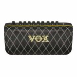 Černý kytarový kombo zesilovač s látkovou mřížkou v kosočtvercovém vzoru. Uprostřed je umístěno zlaté logo VOX. Horní ovládací panel obsahuje řadu če…