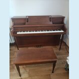 Hnědé dřevěné piano s doprovodnou stoličkou. Nad klávesnicí je vyveden nápis WILLIS. Povrch nástroje i stoličky vykazuje drobné známky opotřebení.