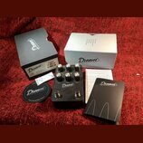 Sada příslušenství a kytarový efekt v černé barvě s nápisem Dream 465 REVERB-AMP. Zařízení má pět ovládacích knoflíků s popisky BASS, MIDDLE, TREBLE…