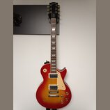 Elektrická kytara s červeným gradientním lakem (sunburst) a krámem z tmavého dřeva. Na hlavě je nápis Gibson a na hrazence nápis Standard. Nástroj má…