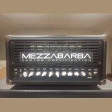 Černý kytarový zesilovač s kovovými rohy. Na přední mřížce je nápis MEZZABARBA CUSTOM AMPLIFICATION. Ovládací panel obsahuje knoflíky s popisky Input…
