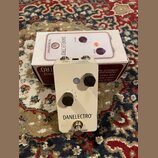 Bílý kytarový efekt pedál značky DANELECTRO s nápisem THE BREAKDOWN™. Na horní straně jsou dva černé otočné knoflíky s popisky VOLUME a BREAKUP (ozna…