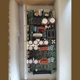 Fotografie zobrazuje elektronickou základní desku s komponenty, která je umístěna v ochranném polystyrenovém obalu. Na desce jsou vidět kondenzátory,…