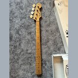 Hrabedlo basové kytary s přírodním dřevěným povrchem a hmatníkem z jasného dřeva. Na hlavě je viditelné logo Fender a nápis Jazz Bass. Nástroj vykazu…
