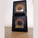 Dvě černé basové reproduktorové skříně naskládané na sebe. Obě mají kovovou mřížku s žlutým kruhem a nápisem Mark bass. Povrch skříně je potažen čern…