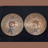 Dvě mosazné činely s výrazným kladivováním a černým logem K ve spodní části. Levý činele má nápisy Custom Special Dry a HIHAT BOTTOM 14" 70 cm. Pravý…