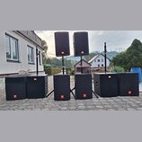 Sada černých reproduktorů značky JBL. V dolní řadě stojí šest subwooferů, dva z nich jsou umístěny na stojanech. Na dvou horních reproduktorech a vše…