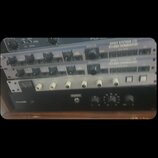 Snímek zachicuje čtyři rackové studiové procesory naskládané nad sebou. Horní dva jsou stříbrné s nápisem APHEX SYSTEMS LTD STUDIO DOMINATOR. Třetí z…