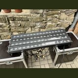 Tři černé lineární LED páse s kulatými světelnými zdroji, umístěné na dvou transportních kufrech. Zařízení jsou propojena černými kabely s žlutými sp…