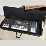 Černý digitální klavír značky YAMAHA, model MODX8, umístěný v černé polstrované přepravní brašně. Na ovládacím panelu je viditelný displej, několik t…