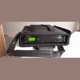 Černý rackový procesor v černé přepravní tašce s popruhem. Na předním panelu je zelený LCD displej a nápisy FRACTAL AUDIO SYSTEMS oraz Axe-Fx ULTRA.…