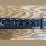 Černý rackový panel s šesti vstupními konektory XLR. Nad každým konektorem je bílý nápis od INPUT 11 do INPUT 16. V pravé dolní části je fialový troj…