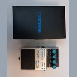 Na fotografii je stříbrný kytarový efekt s nápisy Digital Delay a DD-3T, umístěný před černým krabicem s modrým logem BOSS. Pedal má několik ovládací…