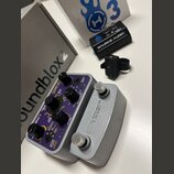 Na fotografii jsou dva efekty značky SOURCE AUDIO v stříbrném kovovém provedení. Levý pedál má fialový ovládací panel s několika otočnými potenciomet…