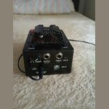 Černý elektronický přístroj s kovovou mřížkou na horní straně. Na zadní straně jsou viditelné nápisy BYPASS, DARK a konektory s popisky PHONES, OUTPU…