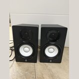 Dva černé regálové reproduktory s bílými membránami basových jednotek a černými výškem. V dolní části každého reproduktoru je umístěno logo Yamaha. P…