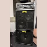 Sada basového zesilovače a dvou reproduktorových skříní. Nahoře je rackový zesilovač s nápisy GALLIEN-KRUEGER a Fusion 550. Pod ním jsou dvě černé re…