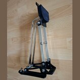 Fotografie zobrazuje černý a chromovaný pedál, pravděpodobně hi-hat nebo basový pedál. Nástroj má kovovou konstrukci s černou základnou a černým nášl…