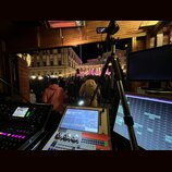 Fotografie zachycuje zvukovou režií s mixážním pultem, dvěma monitory a stativem s kamerou. Na pultu je viditelný nápis Quartz a logo AZ-MUSIC. V poz…