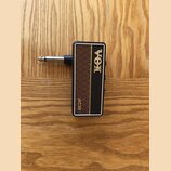 Kytarový kabel s konektorem v hnědém a černém provedení. Na povrchu je zlatým nápisem značka VOX a model AC30. Povrch hnědé části má kosočtvercový vz…