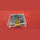 V průhledném plastovém boxu se nachází černý elektrický kytarový snímač. Na povrchu je vidět bílé logo Gibson a žlutá nálepka s nápisem GIBSON SELECT…