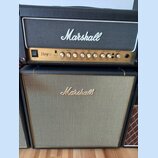 Kytarový zesilovač a reproduktorové boxy značky Marshall. Horní kombo má zlatý ovládací panel s nápisem Haze 100 a sekcemi Effects, EQ a Overdrive. S…