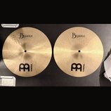 Dvě zlatavé činely z bronzu s viditelným broušením. Oba mají nápisy Byzance a logo MEINL s velkým písmenem M. Na levém činele je text 14" Thin Hihat,…