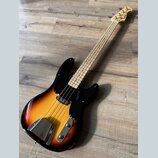 Elektrická basová kytara s tělem v přechodové barvě od žluté po černou a černým pickguardem. Na hlavě hnedku je viditelné logo "Fender". Nástroj má s…