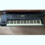 Černý digitální klavír s bílými a černými klávesami. Na levé straně panelu je logo YAMAHA a na pravé nápis MOX6. Horní ovládací panel obsahuje disple…