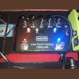 Černý efekt pedál s nápisy MXR a carbon copy deluxe. Na horní straně jsou pětiknobové ovladače s popisky MIX, REGEN, DELAY, SPEED a WIDTH. Jsou zde t…