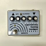Kytarový efekt v kovovém šasi s bílým předním panelem. Na panelu jsou čtyři otočné knoflíky s popisky bias, density, fuzz, filter a volume, přepínač…