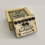 Kytarový efekt v kovovém šasi s béžovým povrchem a ozdobným vzorem. Na pedálu je nápis „Germanium 4 BIG MUFF“ a logo „electro-harmonix“. Jsou zde ovl…