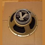 Kruhové reproduktory v zlatavém kovovém rámu s černou membránou. Na středovém krytu je nápis CELESTION, velký symbol V a text G12 TYPE 70-watt oraz C…