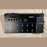 Černý kytarový procesor s nápisem FIREHAWK FX a logem LINE 6. Zařízení obsahuje displej, šest otočných ovladačů s popisky DRIVE, BASS, MID, TREBLE, F…