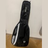 Černý softcase na hudební nástroj s bílým pruhem podél zipu. Na horní části je bílý nápis HERGET a v dolní části se nachází logo ve tvaru štítu s pís…