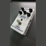 Bílý efekt pedál s nápisy MXR BASS INNOVATIONS a bass compressor. Na horní straně jsou čtyři černé otočné ovířky s popisky RELEASE, RATIO, GAIN REDUC…