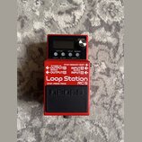 Červený kytarový pedál značky BOSS s nápisem Loop Station RC-5. Na horní části je displej, tři ovládací tlačítka s popisky RHYTHM, SETUP a MEMORY, ot…