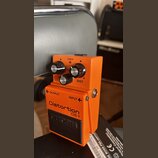 Oranžový kytarový efekt s nápisy Distortion DS-1 a logem BOSS na spodním černém pedálu. Na horní části jsou tři ovládací knoflíky s popisky LEVEL, DI…