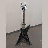 Černá elektrická kytara s tělem ve tvaru hvězdy a chromovanou hlavou. Na hlavě je viditelné logo DEAN. Kytara má dva humbuckery, tři ovládací knoflík…