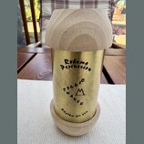 Kovový shaker zlaté barvy s horní a spodní částí z přírodního světlého dřeva. Na kovovém těle jsou černým nápisy „Rohema Percussion“, „Saloio SHAKER“…