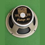 Kruhový reproduktor s béžovým kovovým rámem a černou membránou. Na černé středové krytce je zlatý nápis CELESTION LOUDSPEAKERS, dvakrát označení G12…