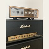Na fotografii jsou dva kytarové zesilovače. Horní zařízení má stříbrný přední panel s dřevěným rámem, logo UNIVERSAL AUDIO a nápisy RIG, ROOM, SPEAKE…