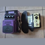 Na fotografii jsou dva kytarové efekty s krabicemi. Fialový pedál má nápisy OVERDRIVE DISTORTION, OD300 a logo behringer. Vedle něj je krémový pedál…