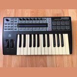 Černý MIDI kontrolér s klaviaturaí, značka novation a model ReMOTE 25SL COMPACT. Zařízení obsahuje klávesy, osm padů, osm otočných enkoderů a několik…